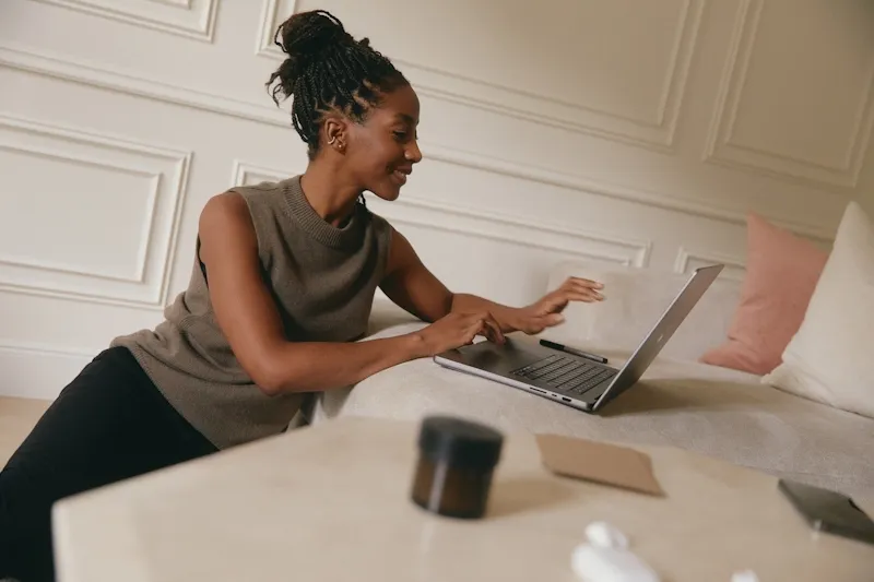 A woman sitting on a bed using a laptop.